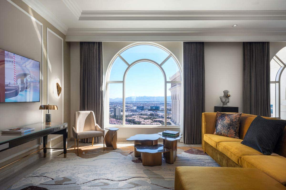 A hotel living room with a large arched window and stylish seating area.