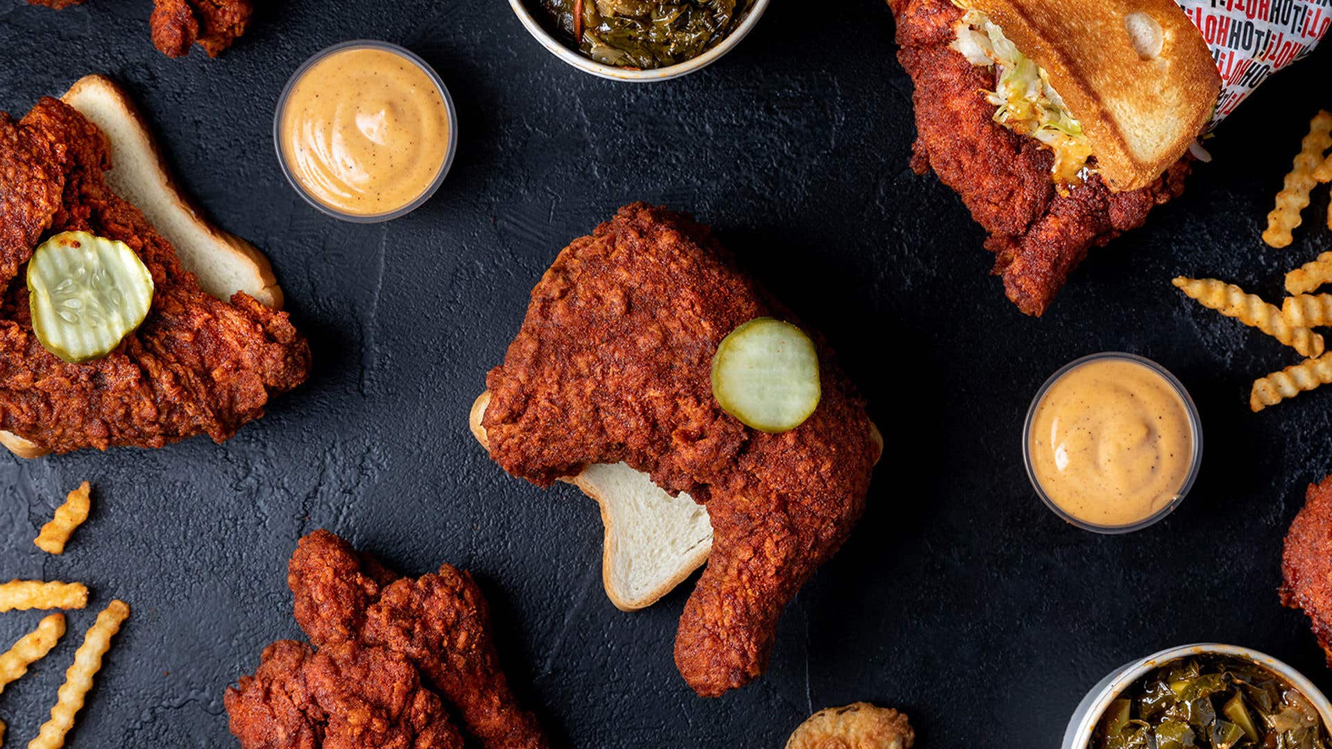Fried chicken, sauce and collard greens displayed on a black table. 