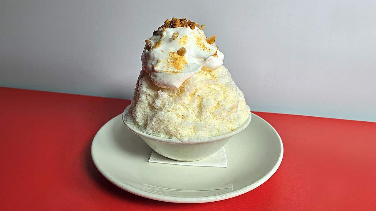 Large mound of shaved ice with crumble  on top in a bowl. 